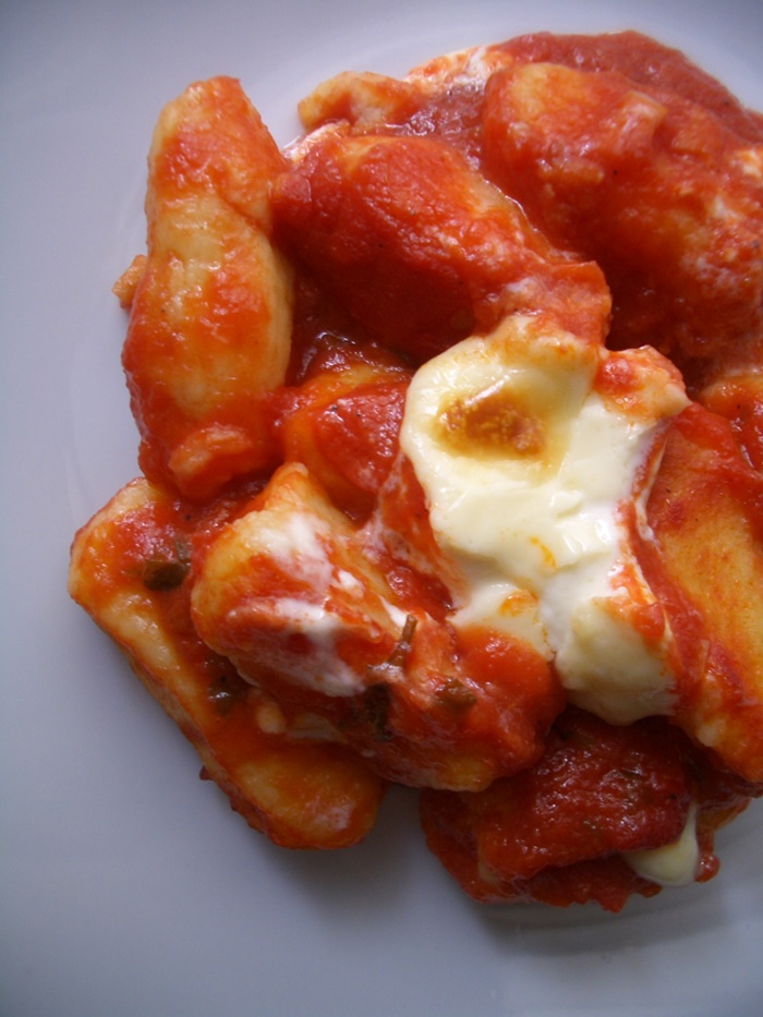 Homemade baked gnocchi with tomato sauce and mozzarella — a true Italian comfort meal Baked gnocchi in rich tomato sauce topped with melted mozzarella