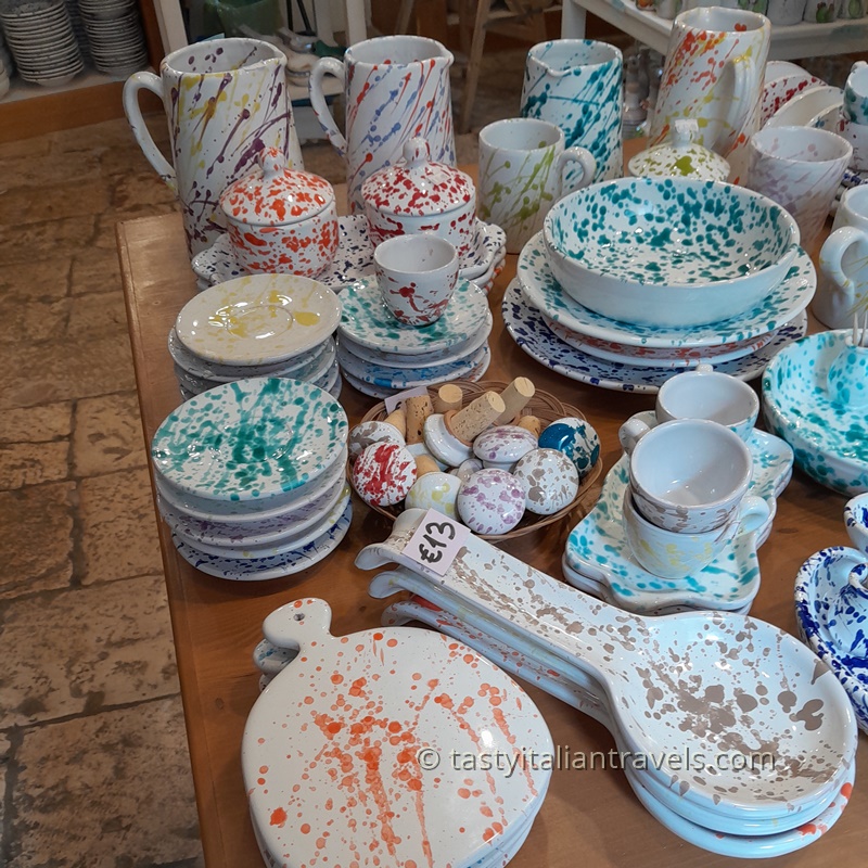 Handmade ceramic products from Puglia, featuring colorful bowls, jugs, and plates with simple natural designs