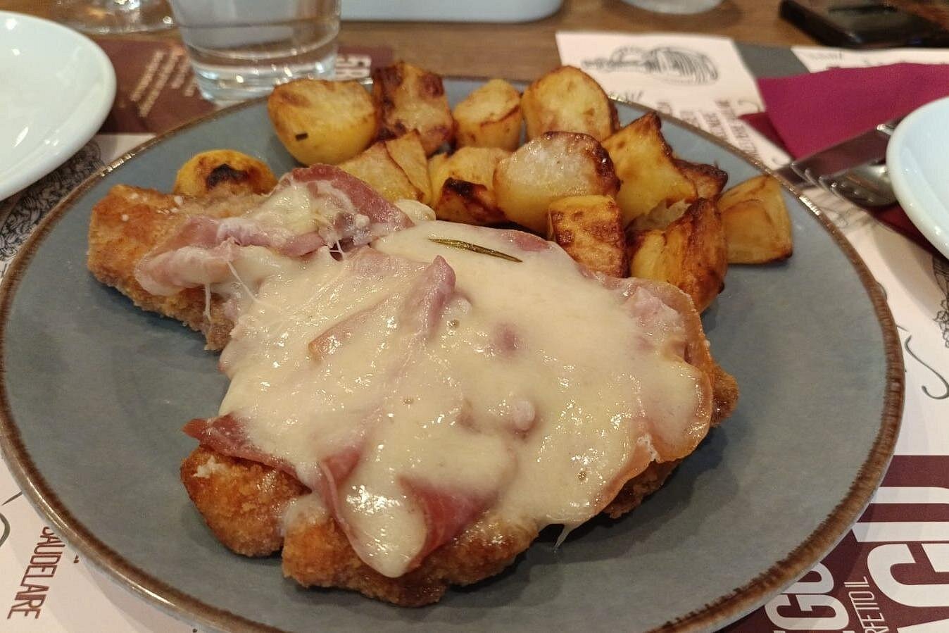 Enjoy "cotoletta alla bolognese", a breaded veal cutlet with prosciutto and Parmesan, served with crispy baked potatoes on the Bologna food tour Delicious "cotoletta alla bolognese" with baked potatoes served during the Bologna food tour