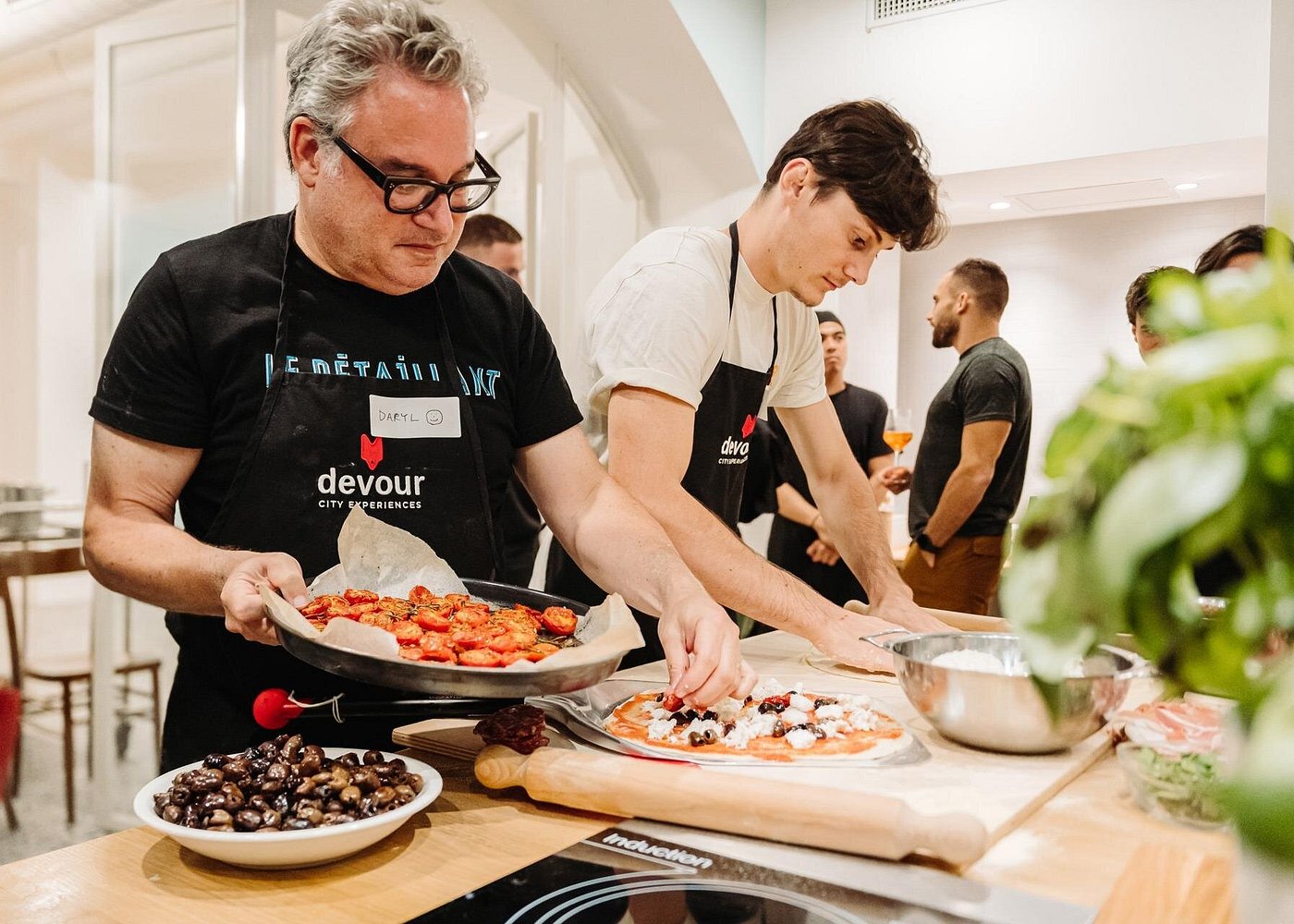Topping pizza with tomatoes and olives at pizza cooking class in Rome Adding fresh tomatoes and olives to pizza dough during a hands-on pizza class in Rome