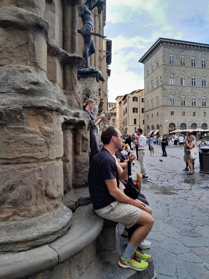 Visitors resting on stone benches at the Loggia dei Lanzi near the Uffizi