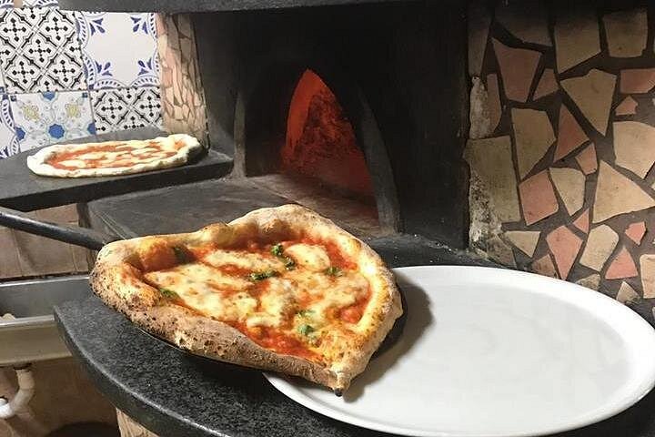 Delicious Neapolitan pizza baking in a wood-fired oven, with golden crust and tempting toppings