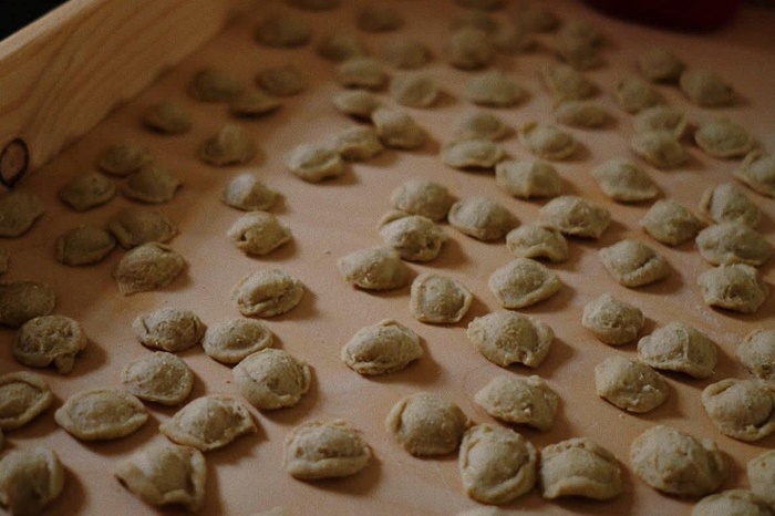 Hands shaping orecchiette pasta dough in a fun Italian cooking class