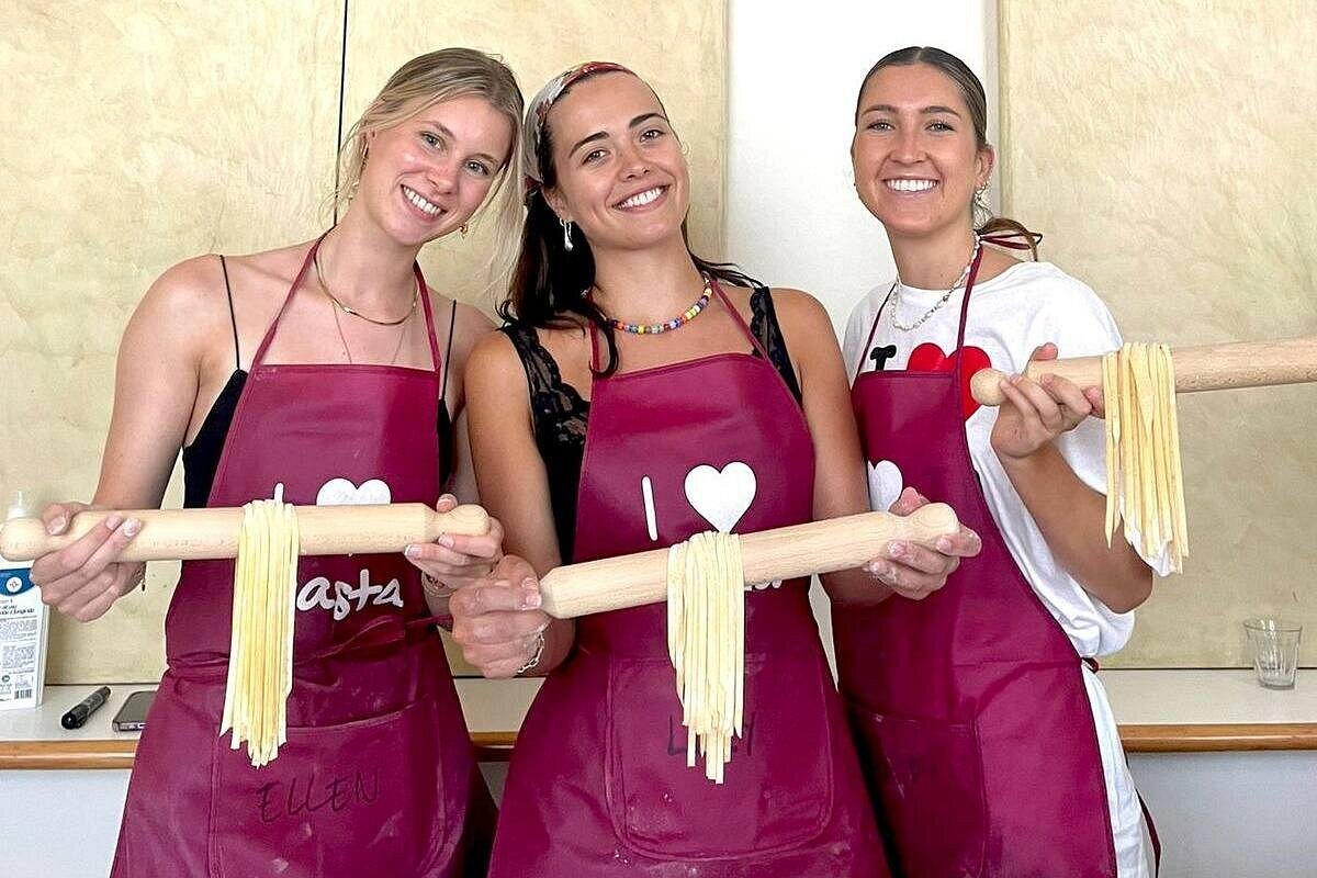 Guests showing off their fettuccine on rolling pins at PastaMania Rome cooking class Guests at PastaMania Rome cooking class holding rolling pins covered in freshly made fettuccine