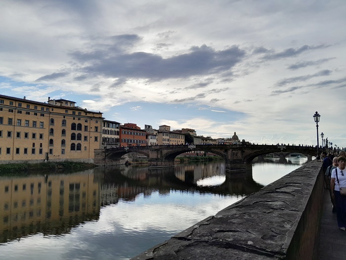Stroll Along the Arno River to Ponte Santa Trinita – A Peaceful Florence Moment View of the Arno River with Ponte Santa Trinita in Florence, surrounded by historic buildings and soft sunlight